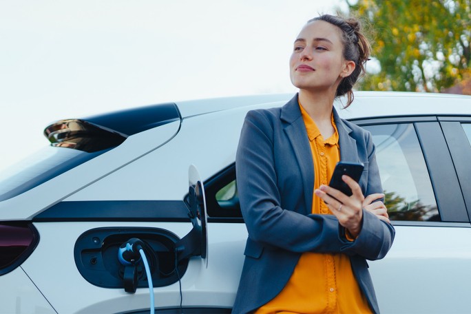 Osoba stoji pored električnog vozila dok se ono puni
